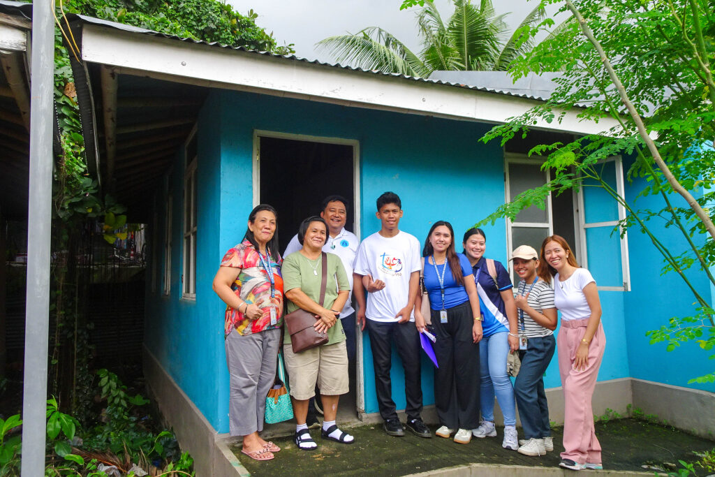 Image shows families stood outside of a house.